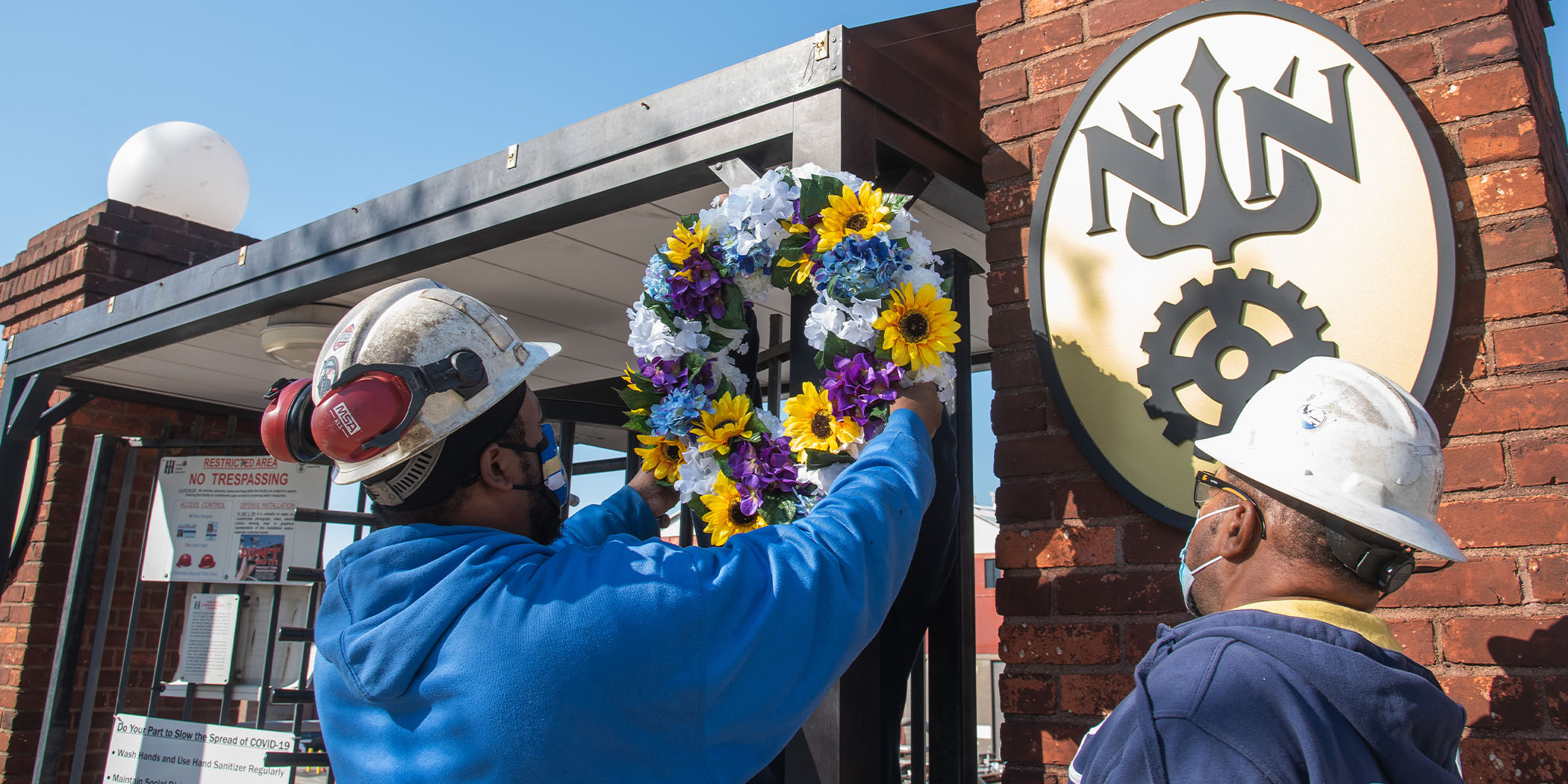 21A-0248-NEWS-WorkersMemorialDayApril28 Shipbuilders hang a wreath at a Newport News Shipbuilding gate for Workers’ Memorial Day. Photo by Ashley Cowan